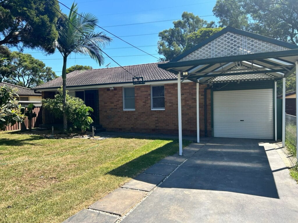 A single-story brick house with a carport and a garage under a clear sky, offering supported independent living in Lethbridge Park NSW.