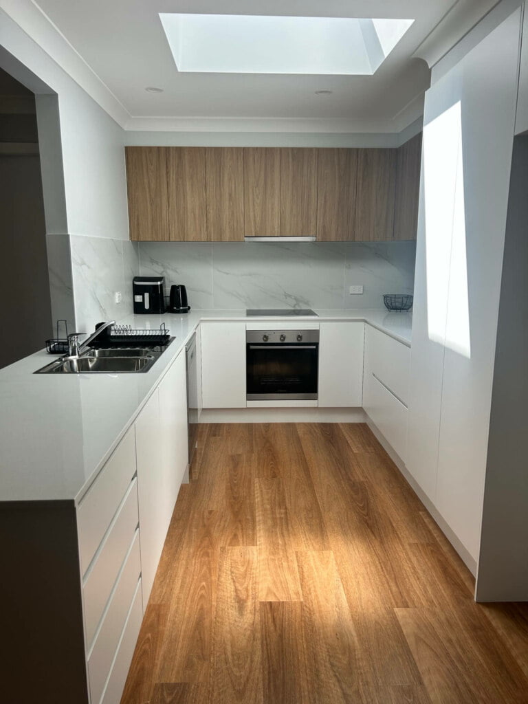 Modern kitchen interior with wooden floor and white cabinetry, ideal for supported independent living in Lethbridge Park NSW.