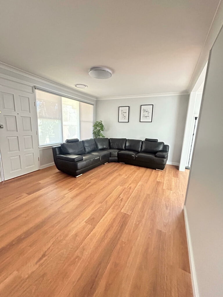 A spacious room with a large sectional sofa and hardwood floors, designed for supported independent living in Lethbridge Park NSW.
