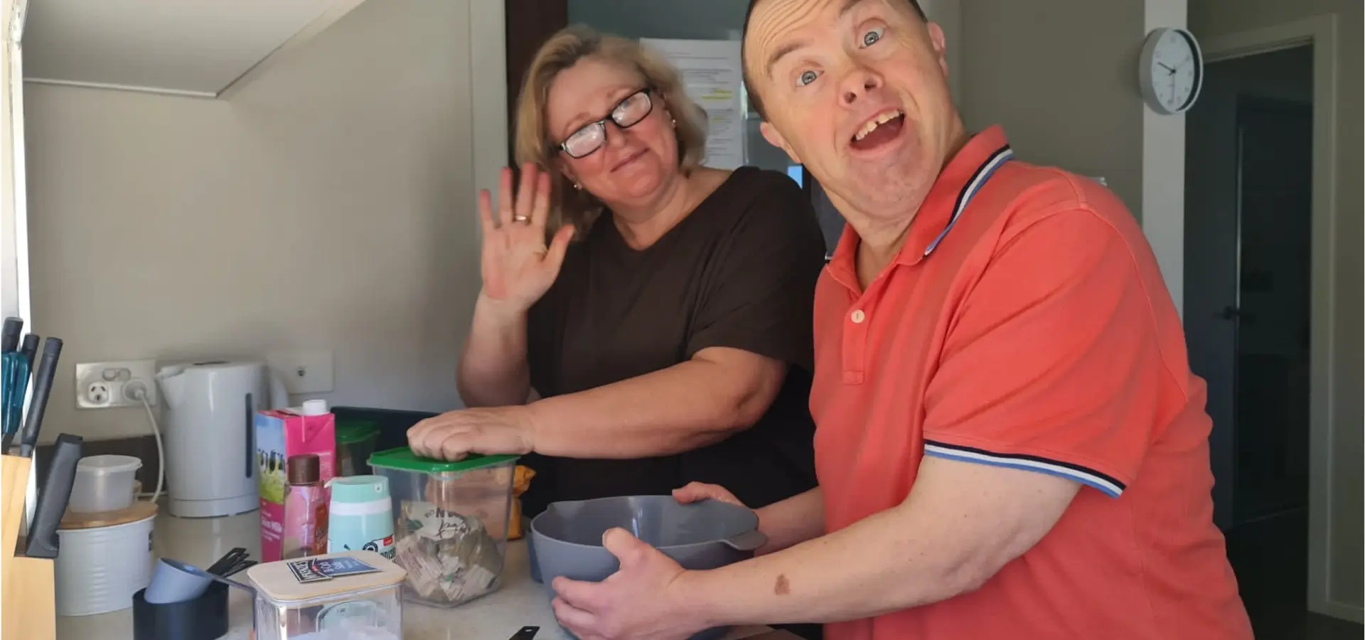 A man and woman in a kitchen making a cake.