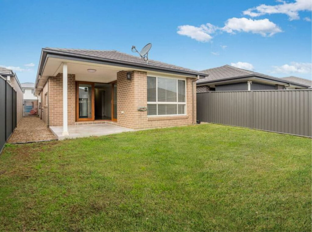 A house with a fence and grass in Ropes Crossing (NSW 2760) backyard.
