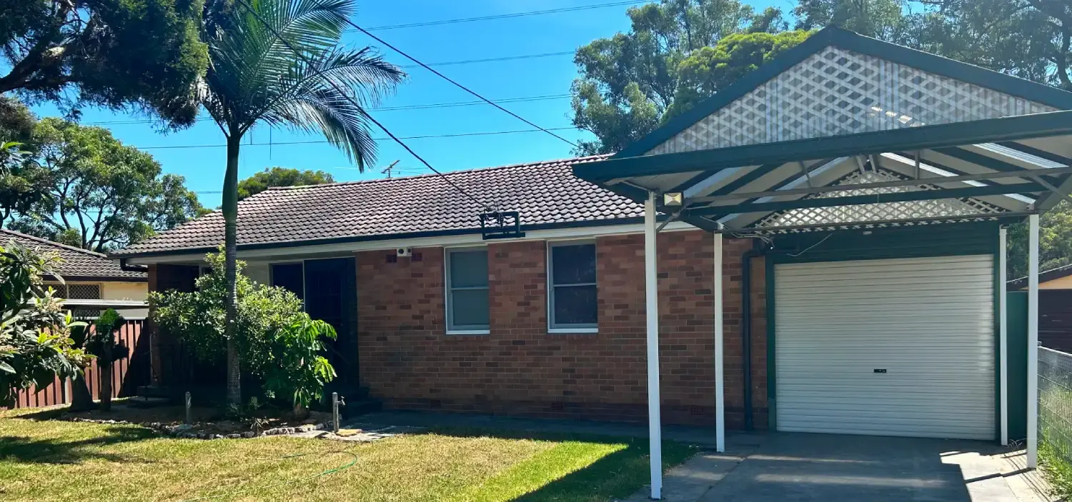 Single-story brick house with a front lawn and an attached carport.
