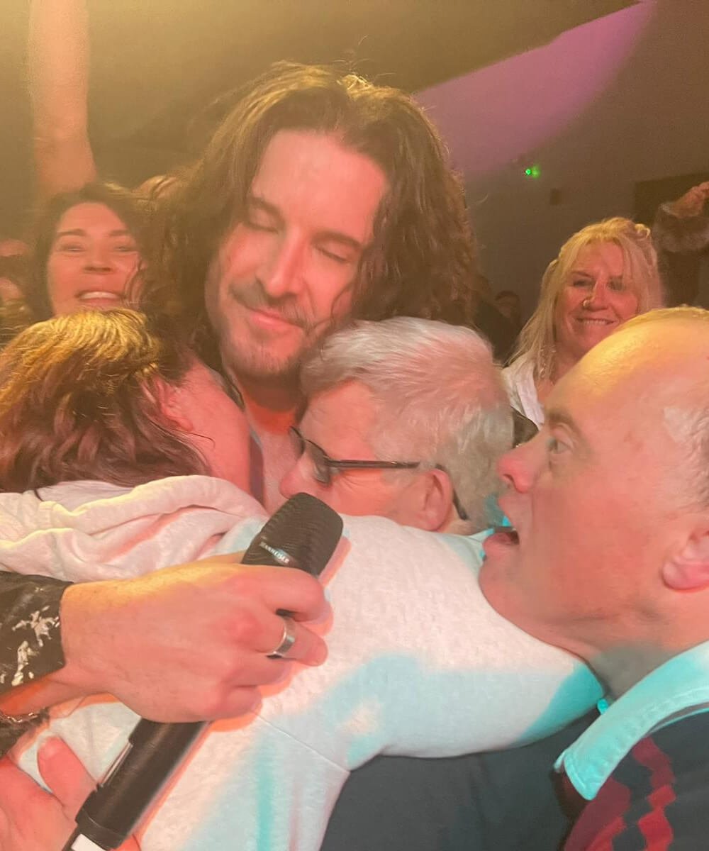 A man is hugging a woman in front of a crowd.